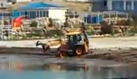 В Севастополе горожане сняли на видео процесс уборки одного из городских пляжей. На нём видно, как экскаватор сгребает на пляже вблизи отеля «Аквамарин» что-то похожее на старые водоросли прямо в море.