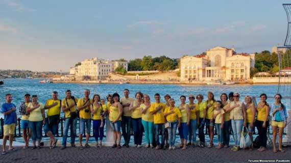 В центре Севастополя, неподалеку от пляжа «Хрустальный», 27 жителей города сфотографировались в желто-голубых одеждах – так местные патриоты поздравили Украину с Днем национального флага